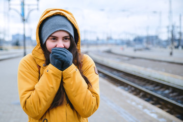 woman waiting for train at railway station. frozen while waiting