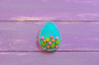 Felt Easter egg isolated on the purple wooden background with empty place for text. Felt egg crafts with plastic flowers and leaves. Happy Easter crafts idea