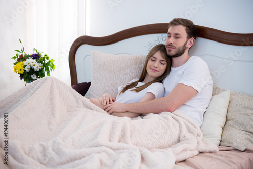 Young Couple Hugging In Bed With Closed Eyes In Modern