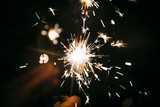 Fototapeta Na sufit - Burning Sparkler in  a party with moody bokeh in the background