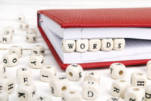 Word Words Written In Wooden Blocks In Red Notebook On White Wooden Table.