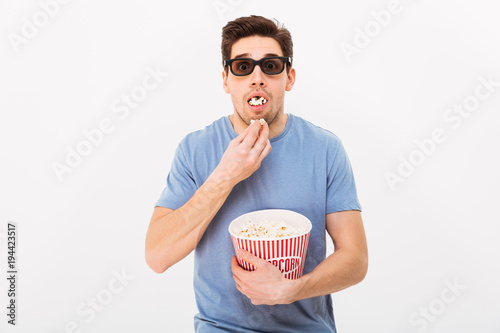 Poster Shocked man in t-shirt and 3d glasses eating popcorn