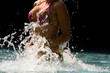 Young beautiful woman making water splash at the pool