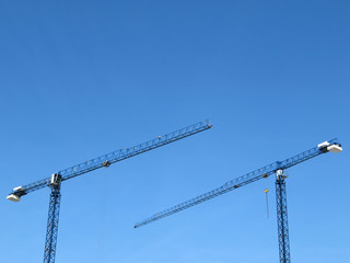 Construction cranes on the background of a clear blue sky. Tower cranes