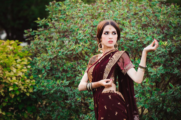 Beautiful young caucasian woman in traditional indian clothing sari with bridal makeup and jewelry and henna tattoo on hands