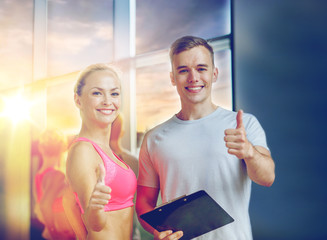 Sticker - smiling young woman with personal trainer in gym