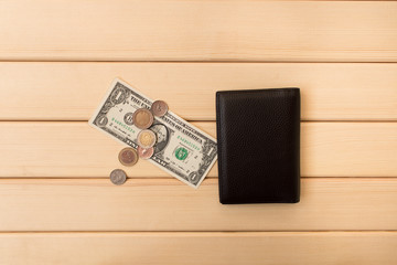 Leather wallet , dollars and coins on the background light wooden table