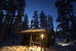 Cabin in winter forest at dusk