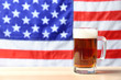 Glass of beer on table against blurred American flag