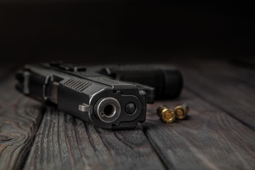 black pistol and cartridges on a wooden background