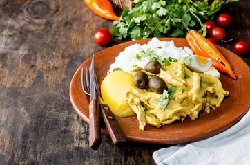 Wall Mural - MEXICAN AND PERUVIAN CUISINE. Aji de gallina. Chicken aji de gallina with olives egg and rice on clay plate. Tipical peruvian and mexican dish