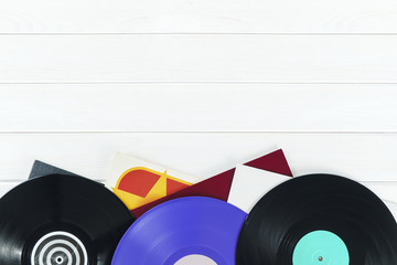 Holiday postcard frame. Background of vinyl records DJs for a music player on a white wooden background close-up. Red, black, violet  vinyl records. Turntable audio equipment for disc jockey