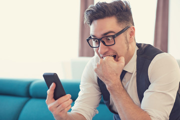 scared man watching phone in fright