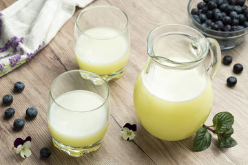 A jug of fresh whey with two glasses and blueberries