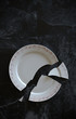 Empty cracked broken plate on black tiled marble background floor or table. 3d illustration