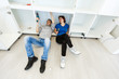 © Angelov - Young woman looking at male repairman examining stove in kitchen