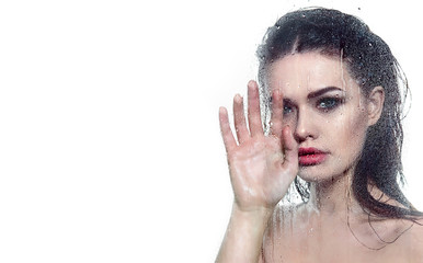 photo of a young dark-haired girl with a make-up smokey holding her hands on a glass with water drops on a white background.