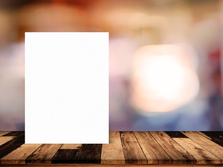 Sticker - White paper poster lean on wood table with blurred interior in cafe background