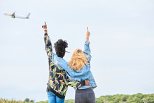 Girls Pointing At Airplane In The Sky.