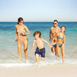 © Trinette Reed/Stocksy - Family running on the beach on vacation in Mexico