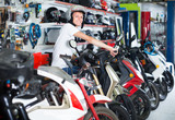 Fototapeta Miasto - Portrait of glad male in helmet on motorbike in the store