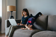 © MaaHoo Studio/Stocksy - Adorable girl playing on sofa, her mom working on laptop