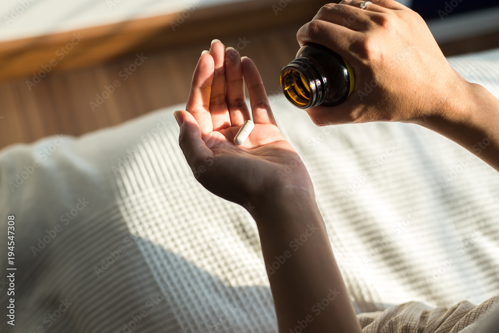 Woman hands with pills on spilling pills out of bottle,Female hand holding a medicine