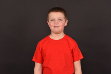 Portrait of a boy on a black background. The child has a good mood. A man in a red T-shirt.