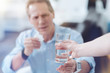 © zinkevych - Take it. Selective focus of glass with water being given to the nice upset handsome man