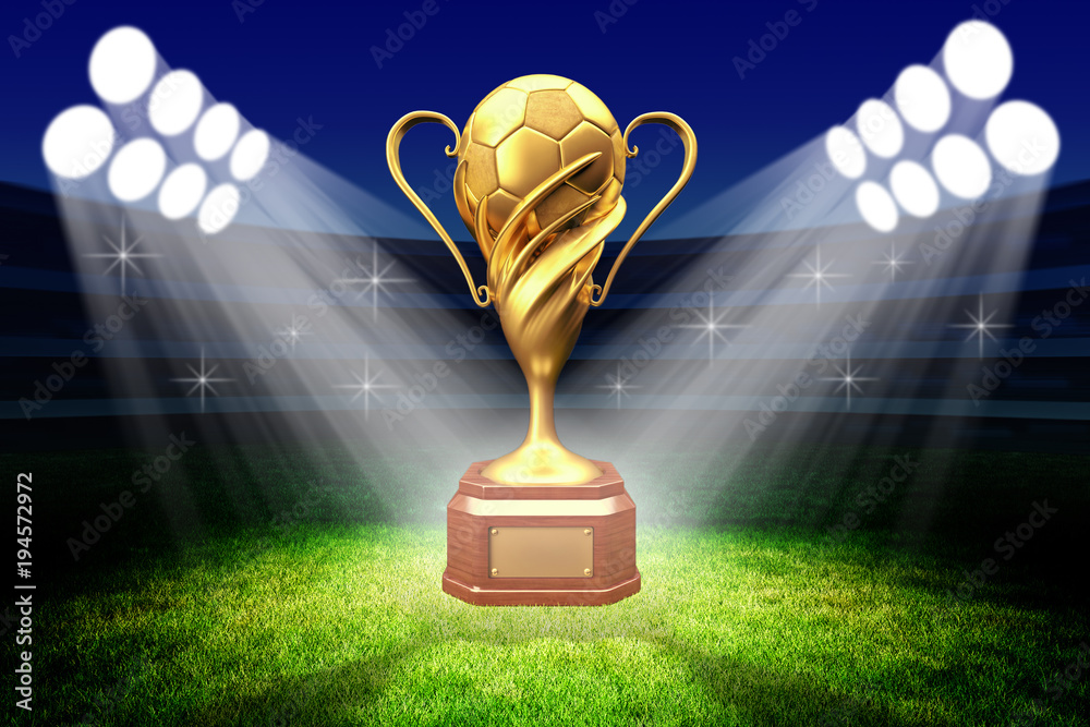 Golden football trophy award ceremony with spotlight illumination on green stadium grass