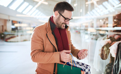 Shopping time. Young man in shopping mall looking for presents. Consumerism, shopping, lifestyle concept