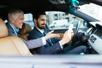 Wall Mural - Senior businesswoman sitting in limousine and talking with her driver. Business concept. 