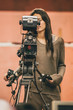 Behind the scene. Female cameraman shooting film scene with camera