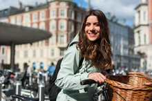 Young Happy Woman On Bicycle Looking At Camera And Smiling In The City Of Copenhagen, Denmark. Activity, Healthy Lifestyle And Environmentally Friendly Transport