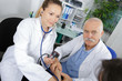 © auremar - senior doctor and young internist woman checking patients blood pressure