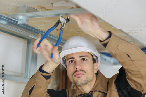 Workman using pliers on metal framework Tableau sur Toile