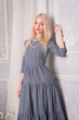 © pushann - A blonde girl in a vintage gray dress stands at the wall of a waist portrait.