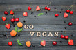 © somemeans - Inscription Go vegan and fruits. Black wooden background. Food concept