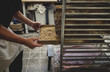 © Maskot - Baker holding tray on rack