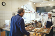 © Maskot - Smiling female owner showing fresh baked food to customer at bakery