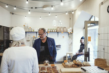 Male Customer Buying Food From Owner At Bakery