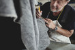 © Maskot - Close-up of senior craftsperson working on gray fabric at workshop
