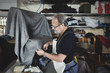 © Maskot - Upholsterer cutting gray fabric