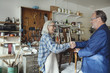 © Maskot - Senior owner shaking hands with customer while selling wooden chair at workshop