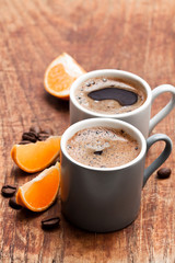 Espresso  with slices of mandarin on rustic wooden table