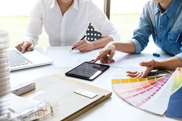 Poster - Two young women interior design or graphic designer working on project of architecture drawing with work tools and color swatches, colour chart in digital tablet at workplace