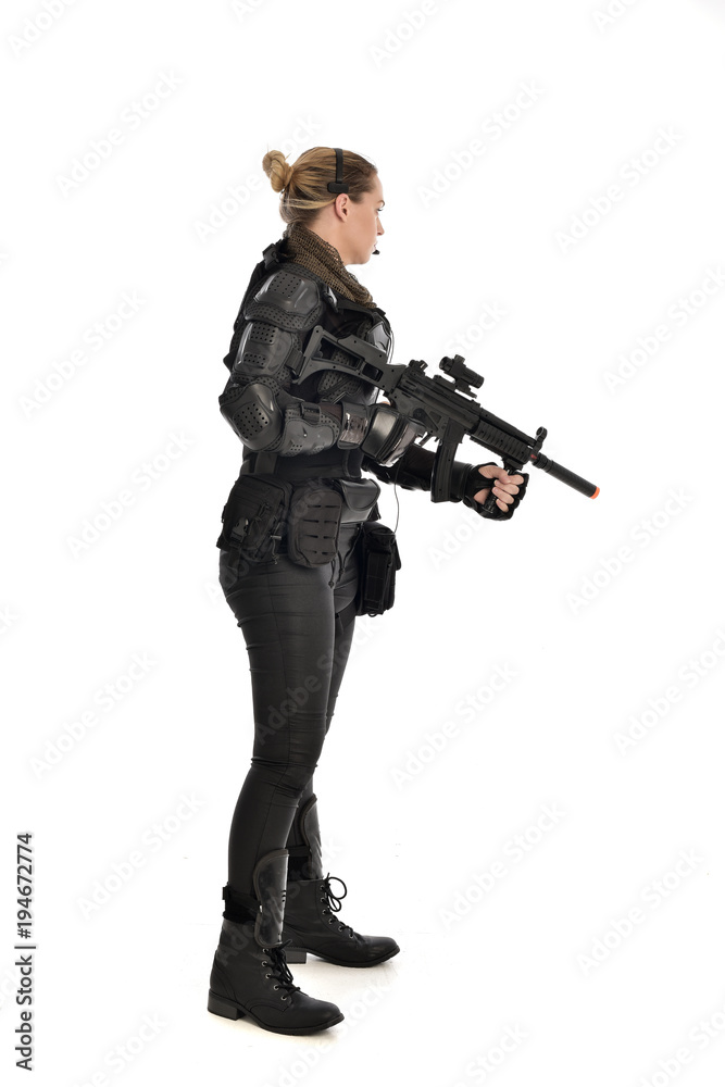 full length portrait of female soldier wearing black tactical armour ...