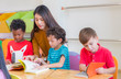 © weedezign - Asian female teacher teaching diversity kids reading book in classroom,Kindergarten pre school concept.
