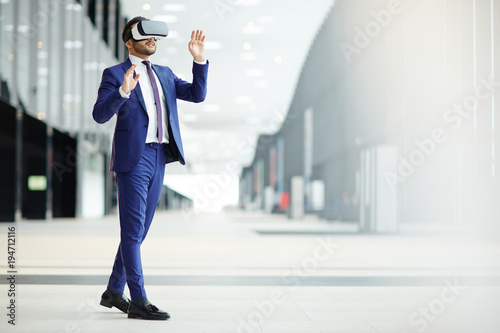 Cuadros en Lienzo Businessman in elegant blue suit and vr headset taking part in virtual conferenc