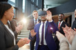 © pressmaster - Young employee or politician in vr goggles touching virtual display while his colleagues applauding to him